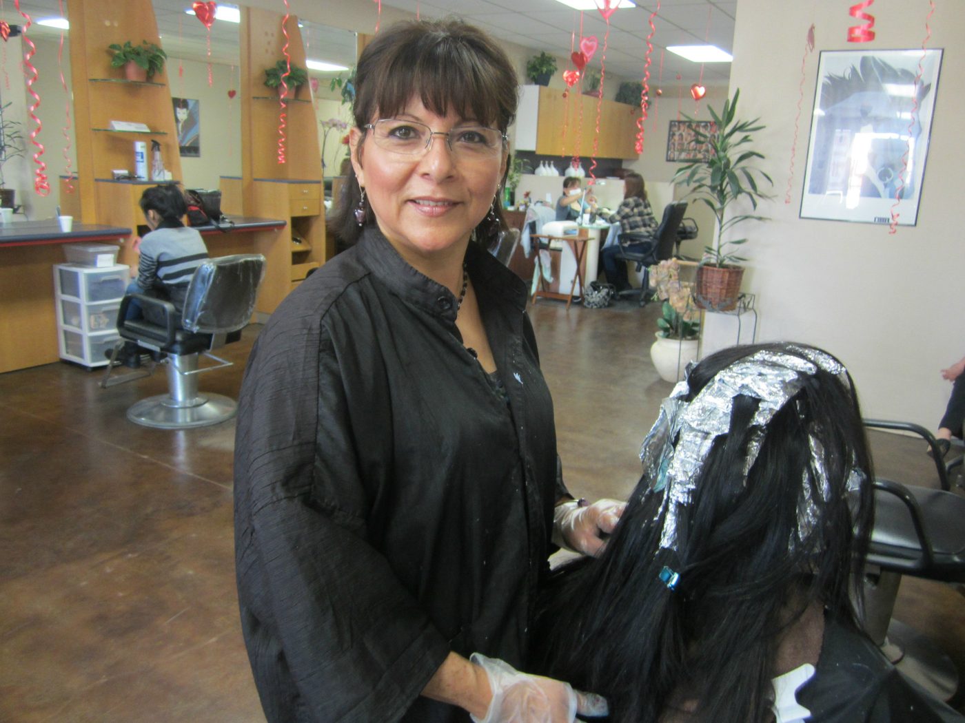Stylist applying foil highlights to a client's long dark hair in the salon